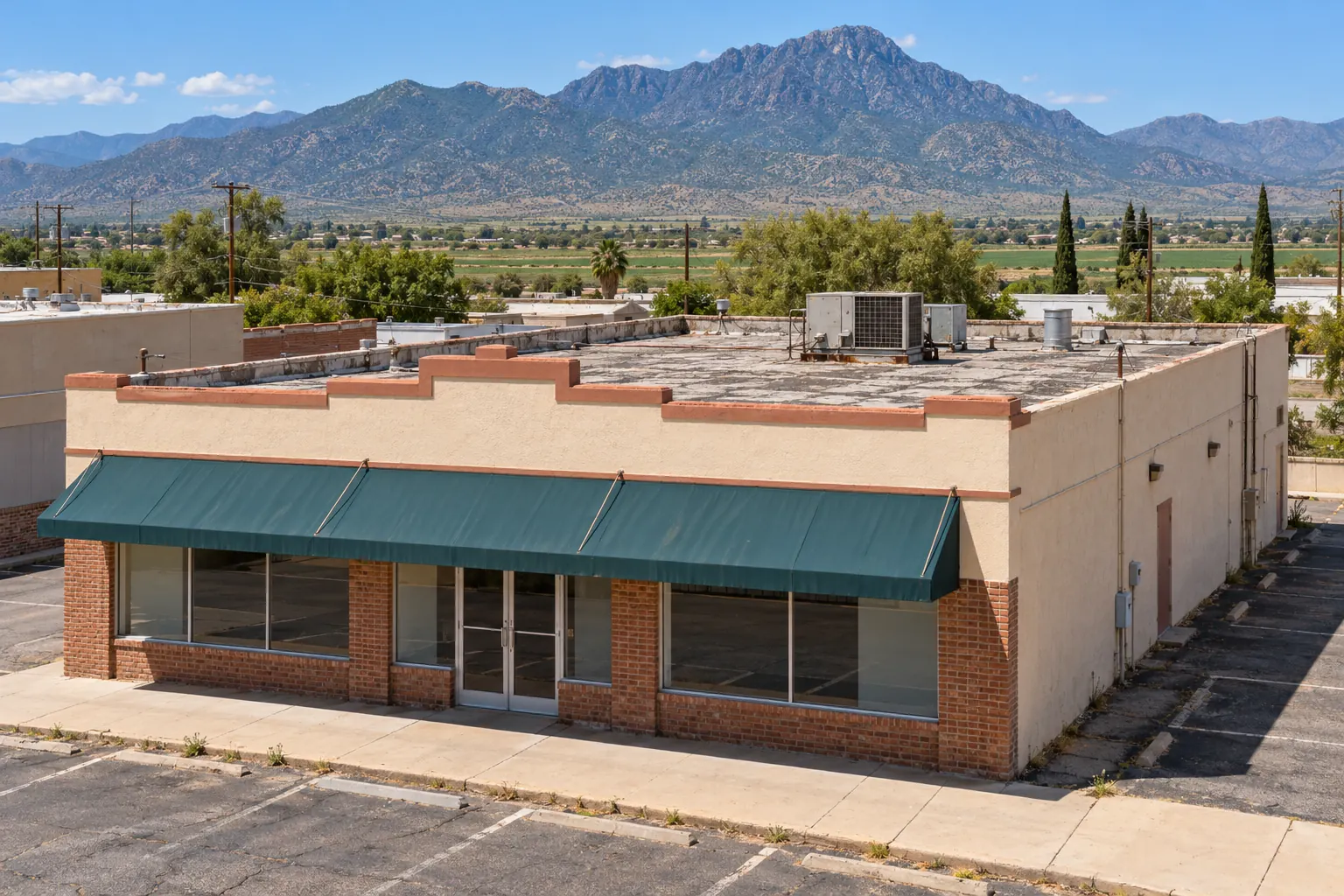 Older brick and stucco storefront with a flat roof, stepped parapet, and rooftop unit
